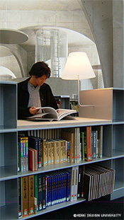 図―4：多摩美術大学図書館大型本書架。大型本書架のところどころに設けられている閲覧台。大型本(美術書)を書架から取り出して閲覧席に運ぶ前にブラウジング(パラパラと内容を確認)するための立ち読みテーブルとなる。このようなブラウジングを快適なものとする(誘導する)ため、スタンド(照明)を取り付けている。デザイン：藤江和子。
